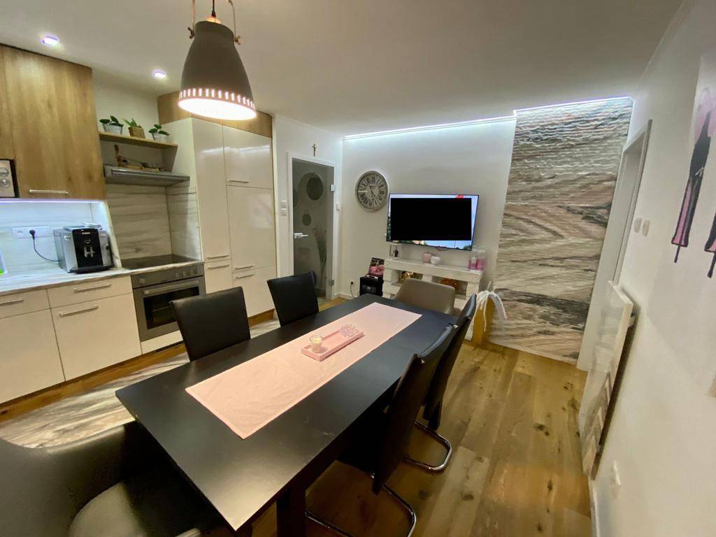 Offener Wohnbereich mit moderner Küche, Esstisch und Holzboden, ideal für geselliges Beisammensein.