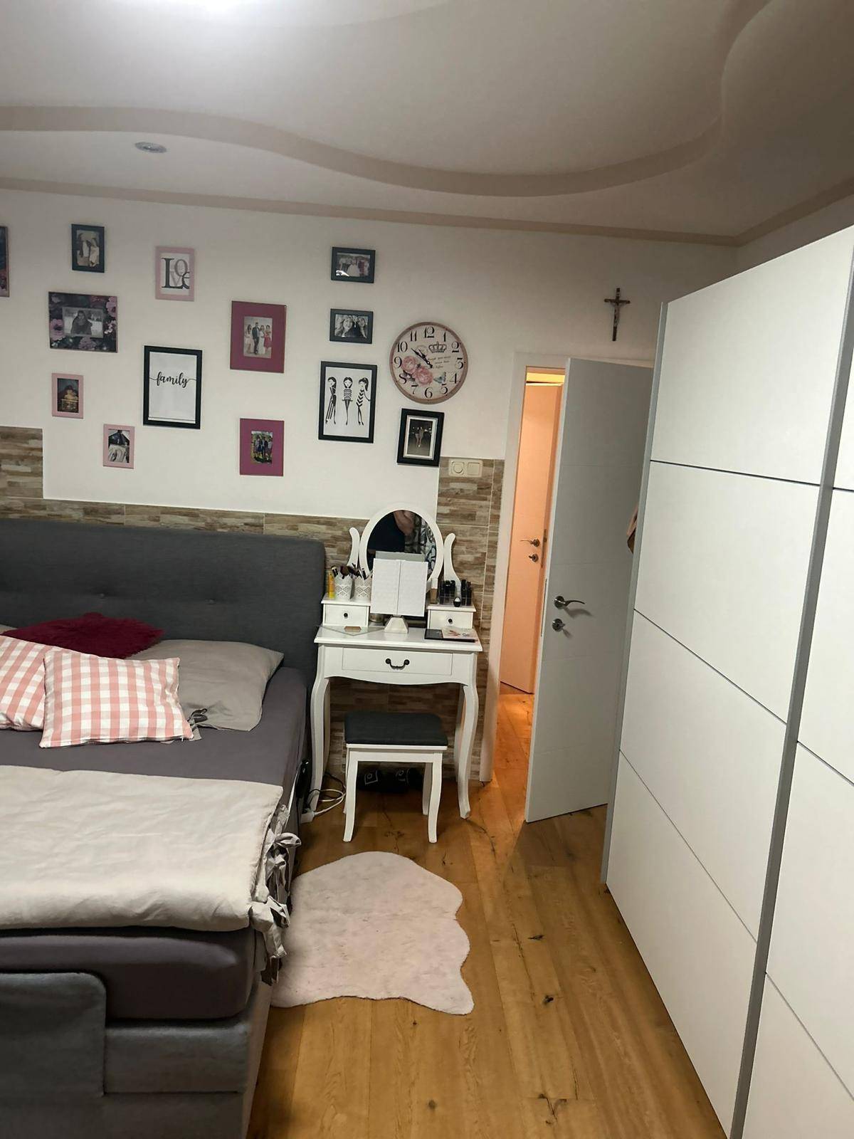 Gemütliches Schlafzimmer mit großem Bett, Schminktisch und persönlichen Dekorationen an der Wand.