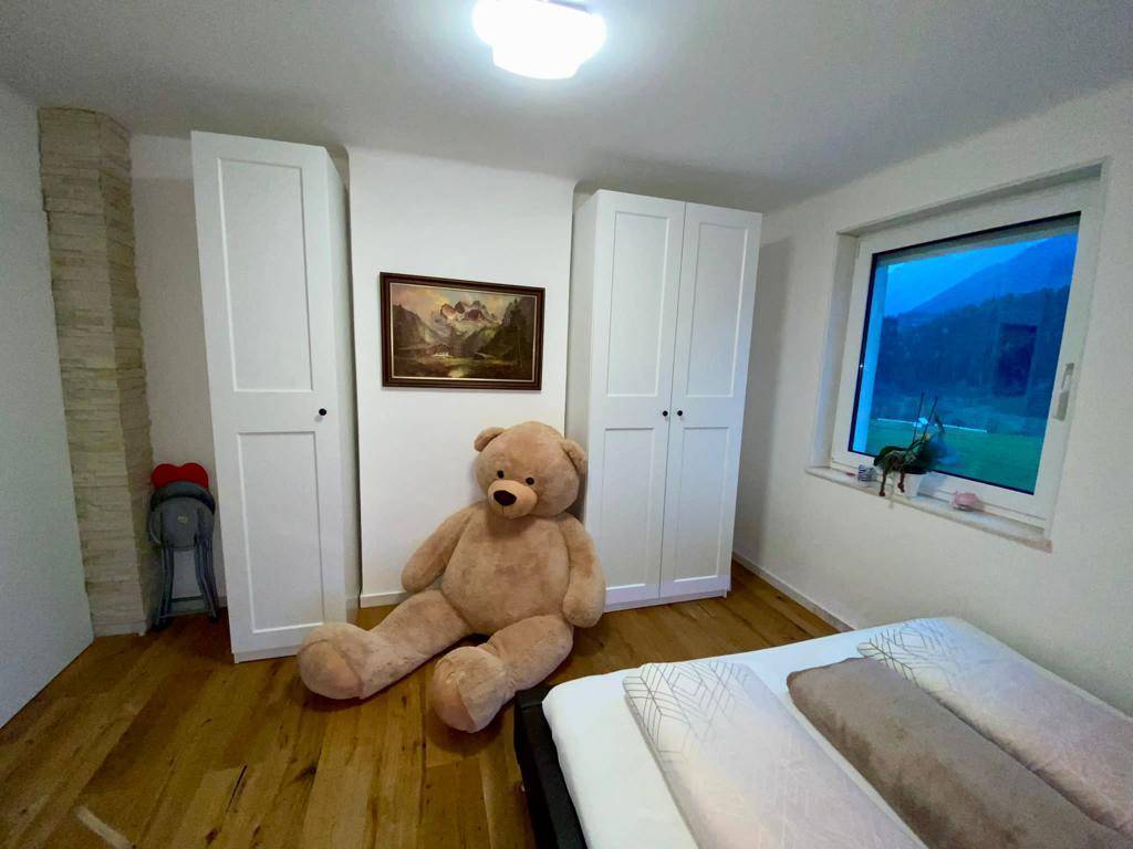 Gemütliches Schlafzimmer mit Holzboden, weißen Kleiderschränken und einem großen Fenster mit Bergblick.