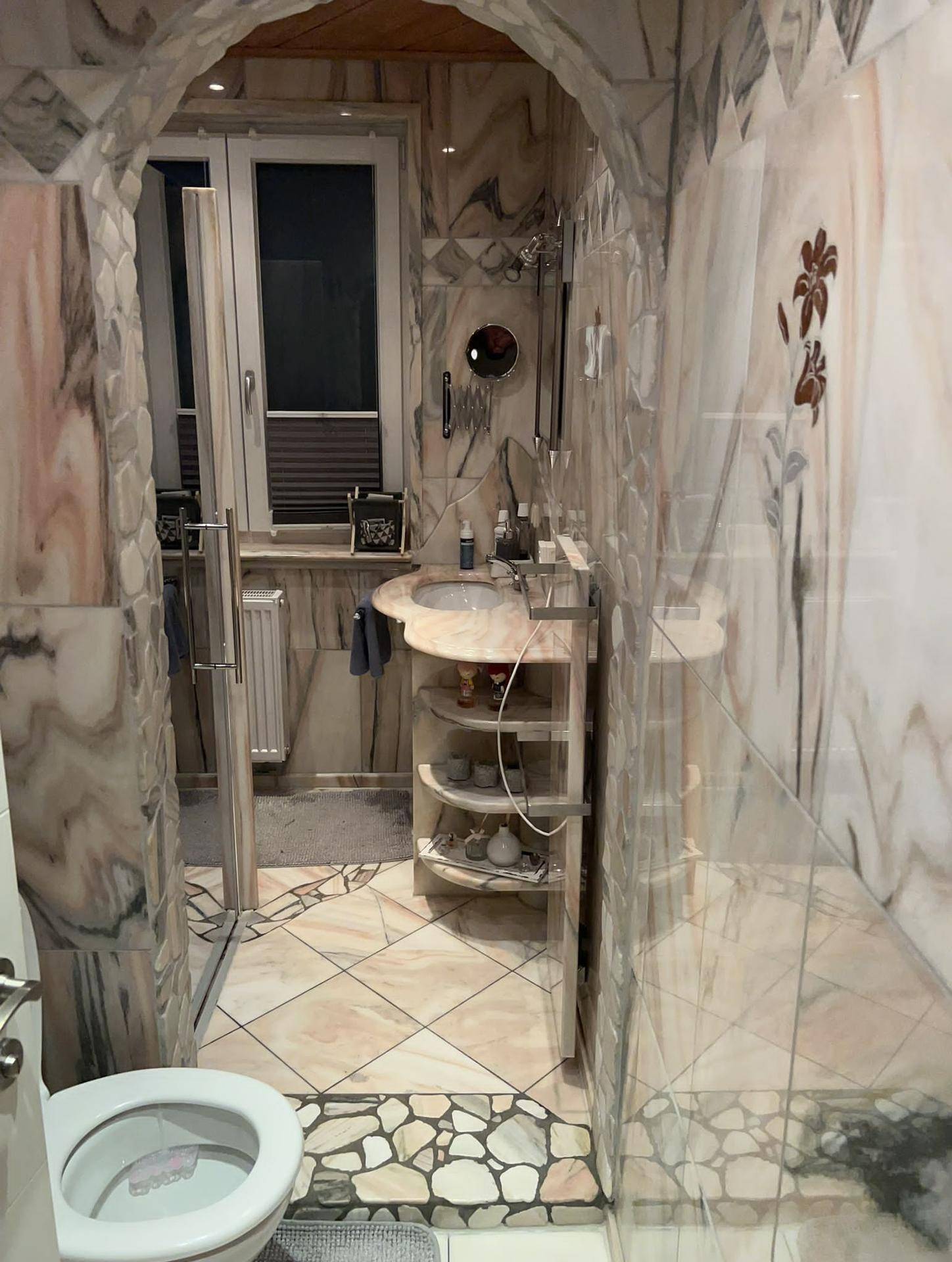 Individuell gestaltetes Badezimmer mit auffälligen Marmorfliesen, Dusche und modernem Waschtisch.