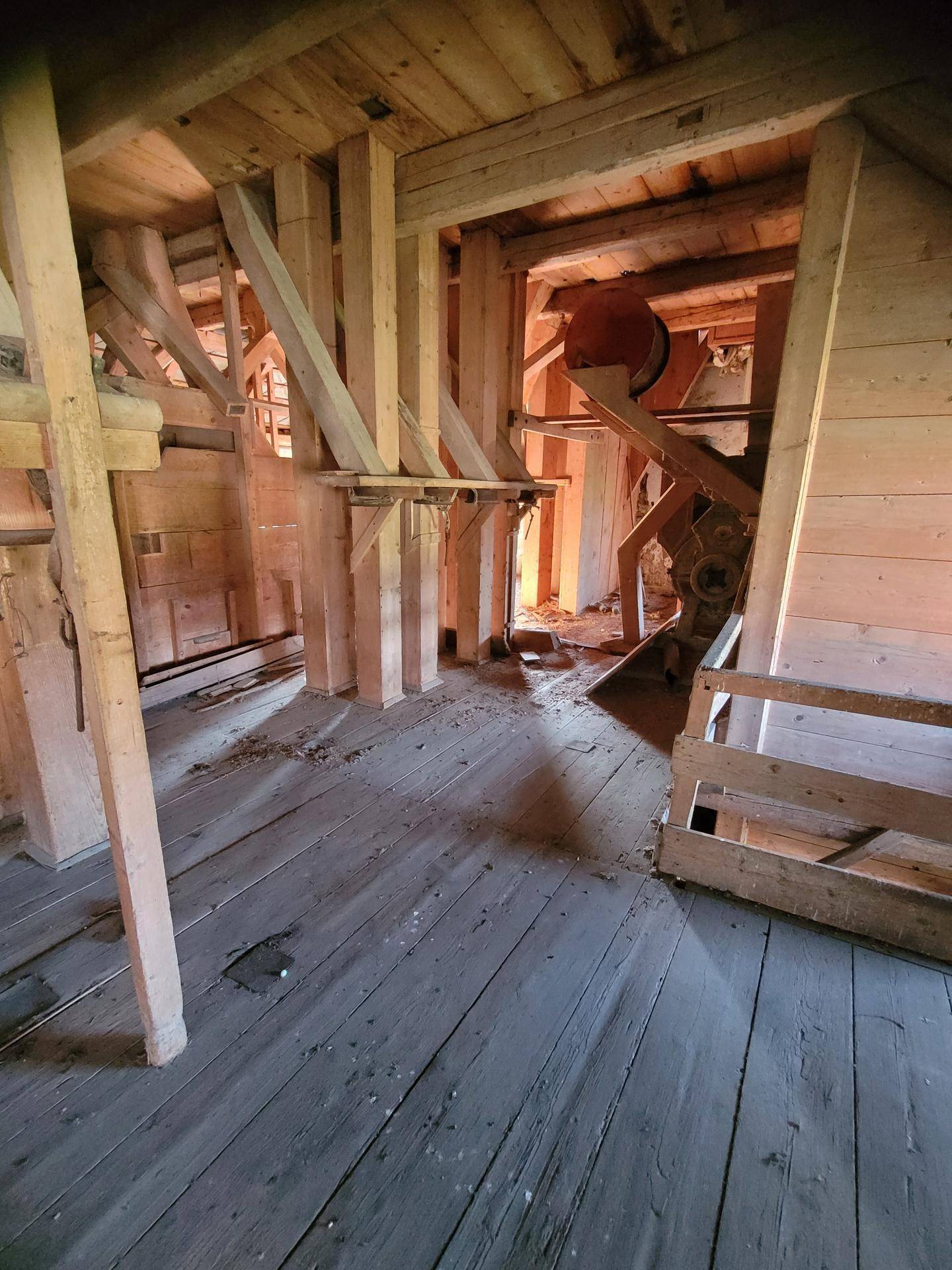 Langer Raum mit Holzboden und sichtbaren Holzbalken, der auf eine industrielle Nutzung hindeutet.