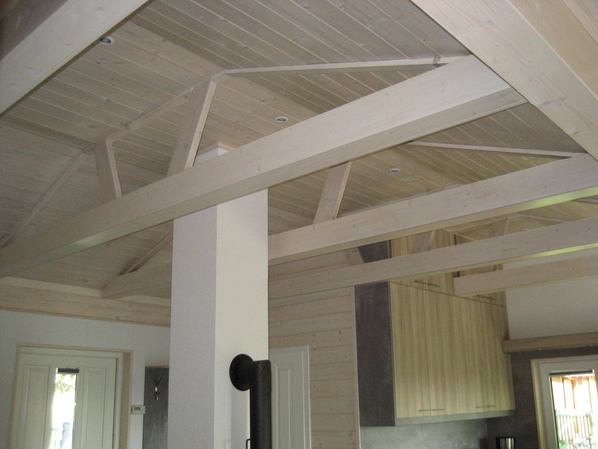 Offene Holzdeckenkonstruktion mit sichtbaren Balken und heller Holzvertäfelung, schafft Raumgefühl.