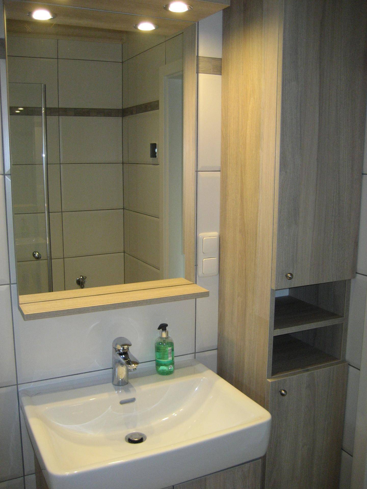 Detailansicht des Badezimmers mit Waschbecken, Spiegelschrank und integrierter Beleuchtung, modern.
