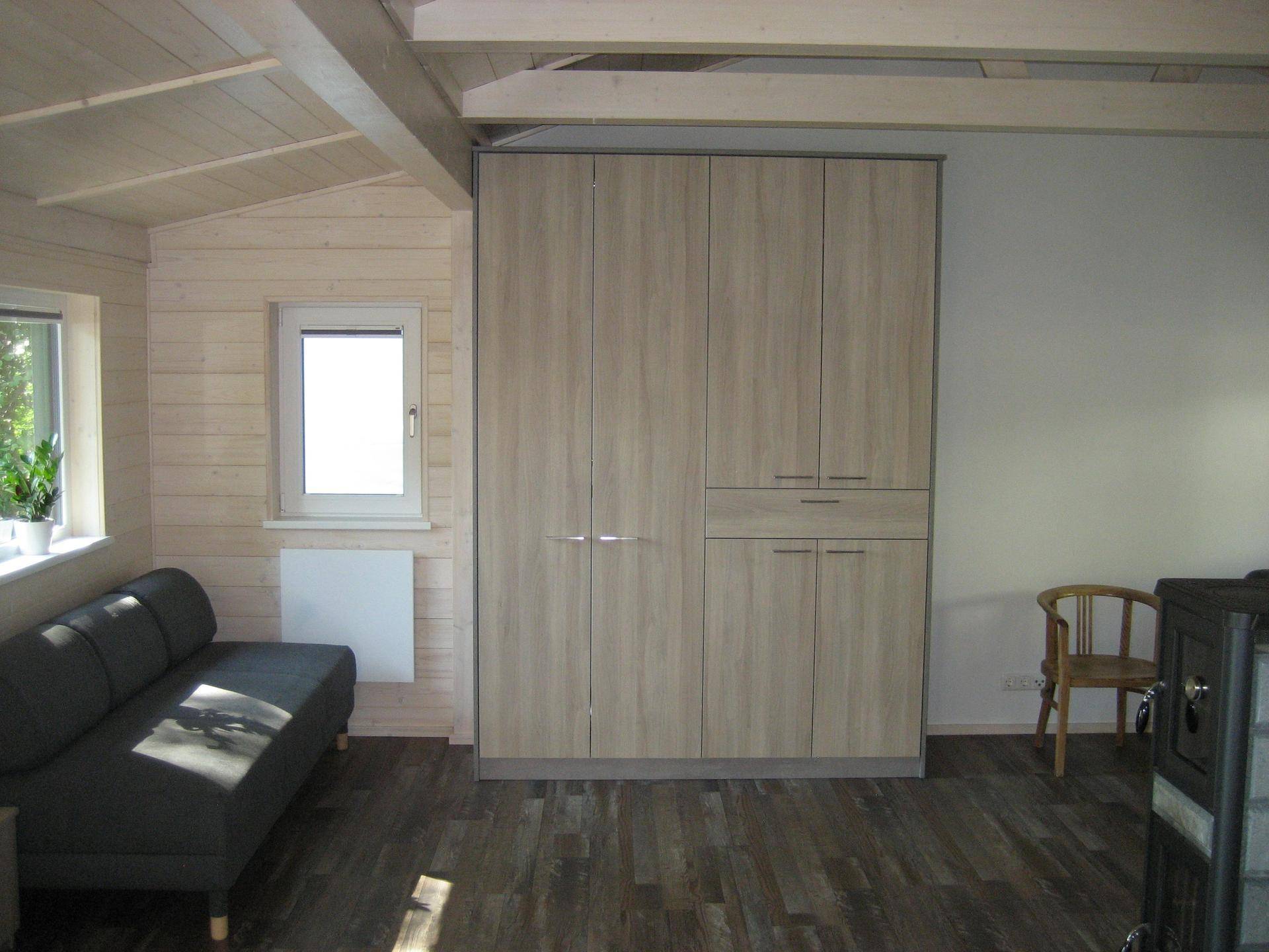 Heller Wohnraum mit Sofa, großem Einbauschrank und Holzvertäfelung, mit hohen Decken.