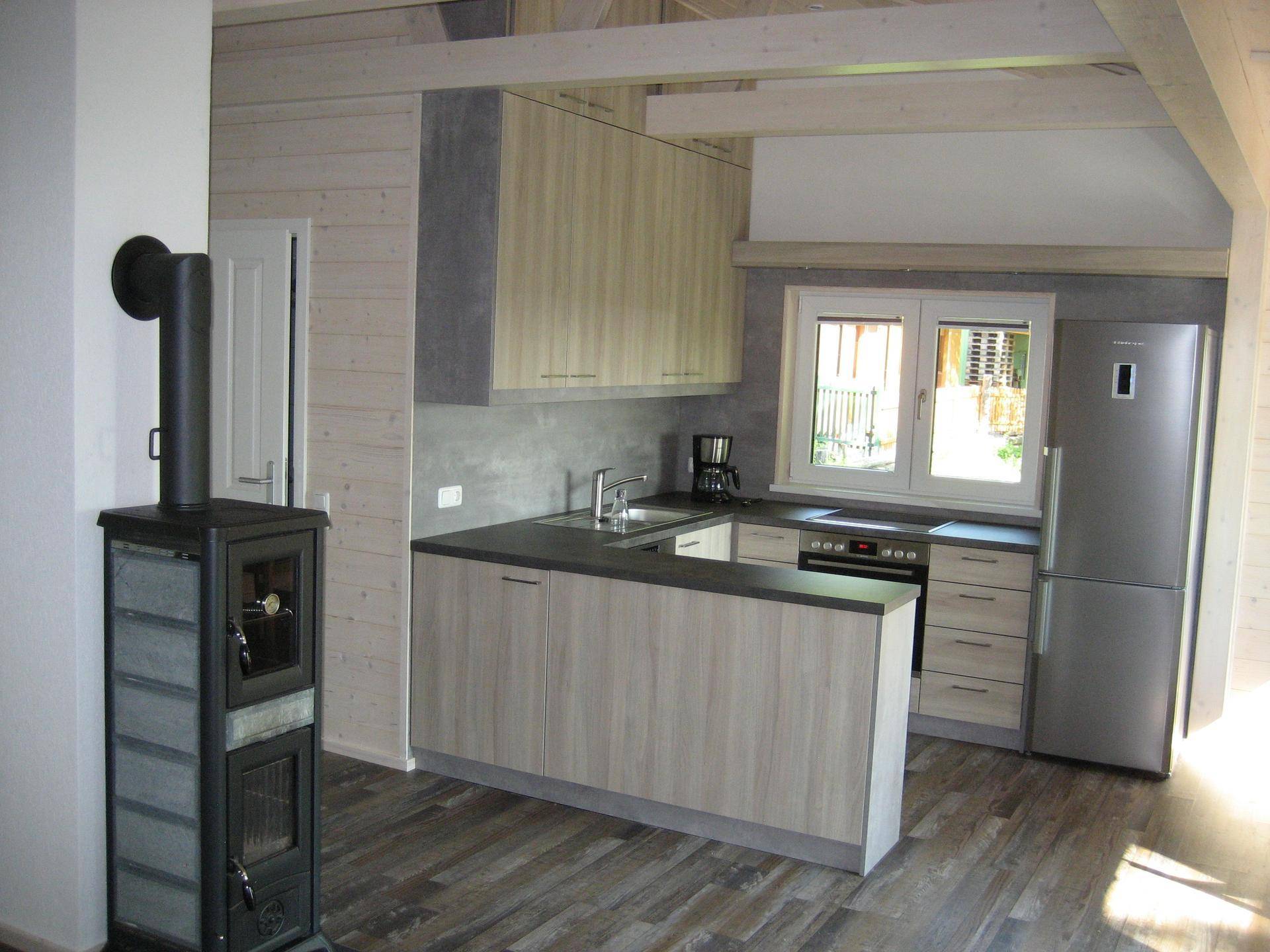 Moderne offene Küche mit integrierten Geräten und Kaminofen, ideal für gemütliche Kochabende.