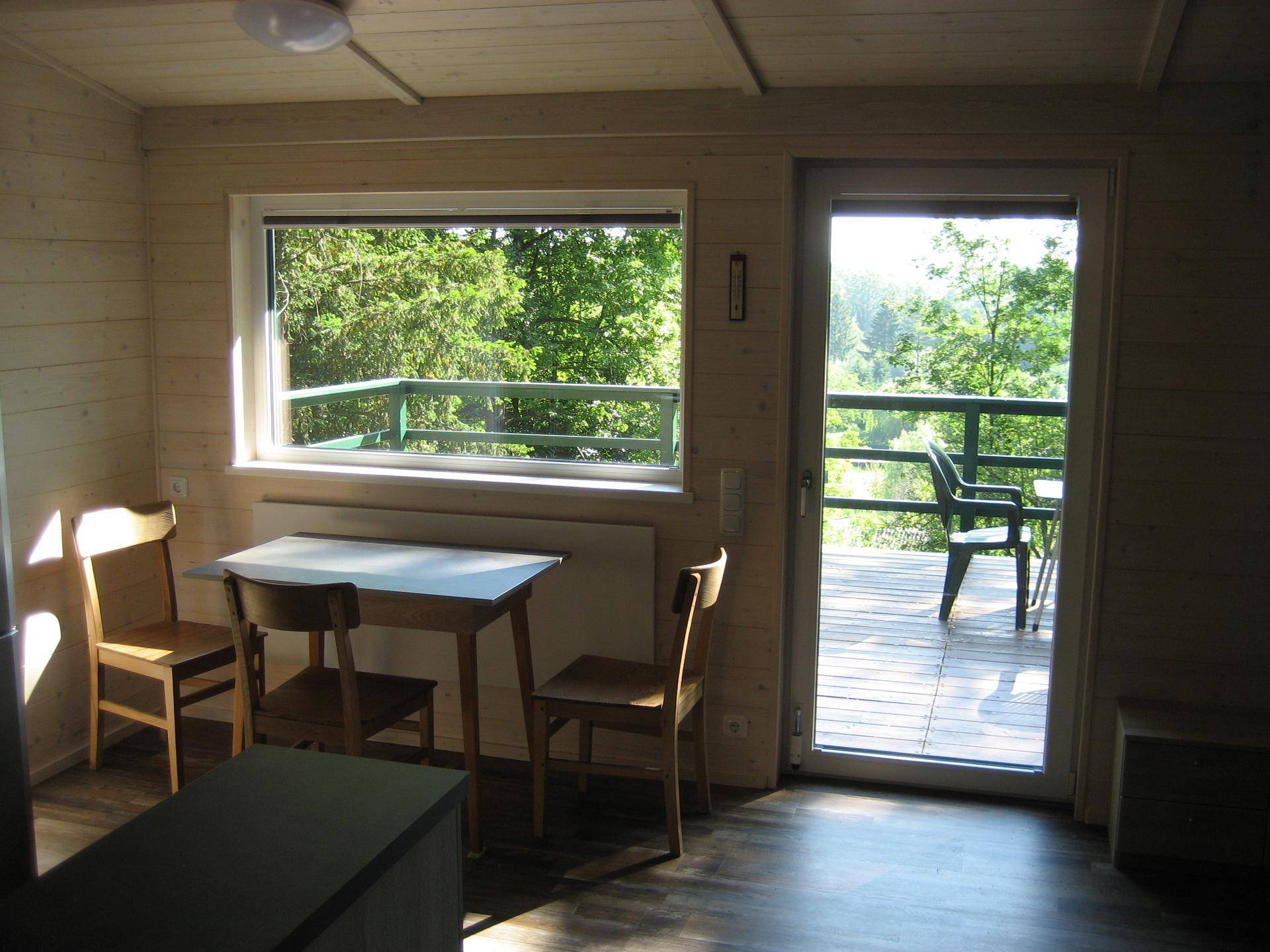 Essbereich mit Holztisch und Stühlen, direktem Zugang zur Terrasse und schönem Waldblick.