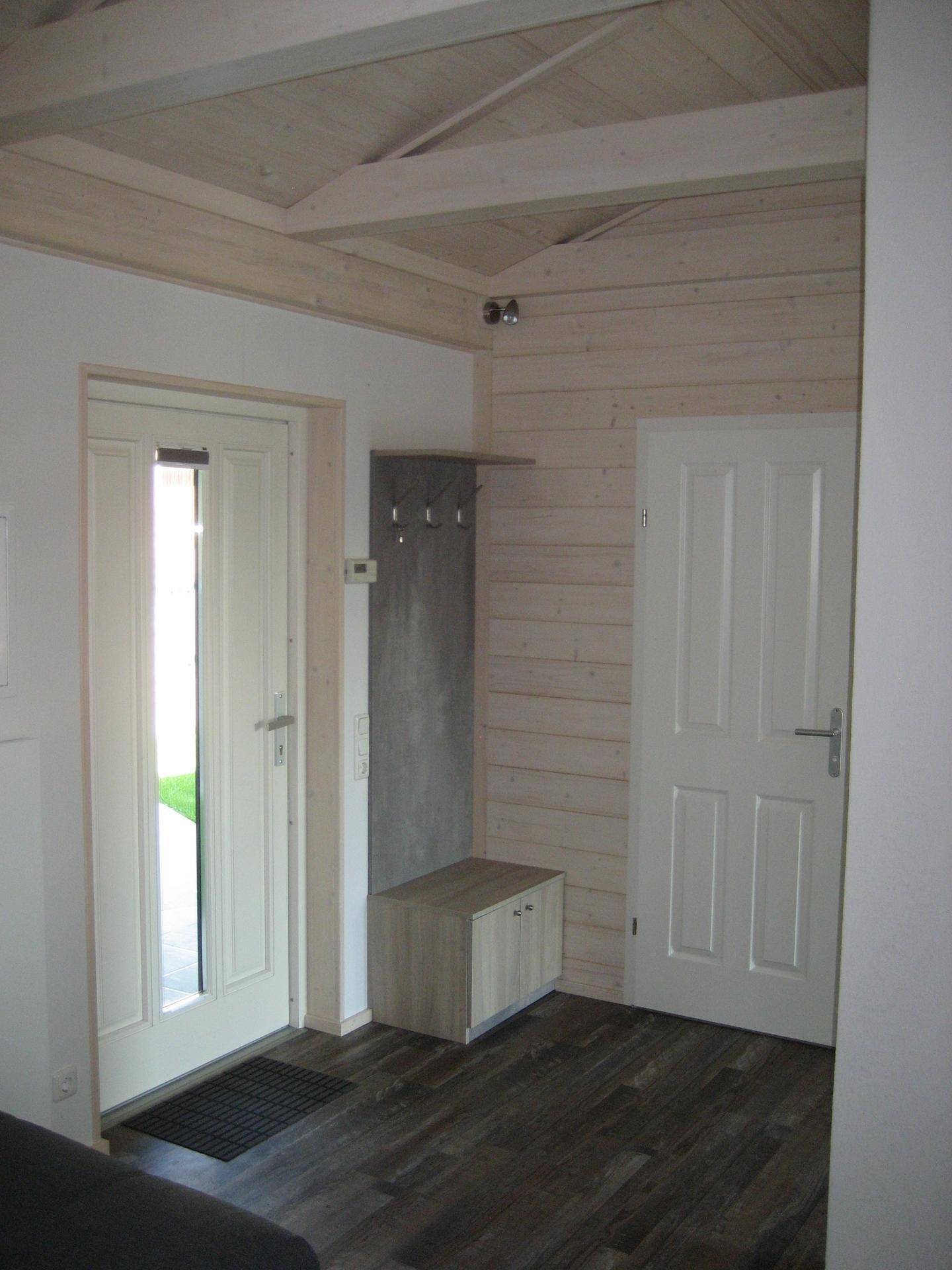 Heller Eingangsbereich mit Garderobe, Schuhschrank und Holzboden, einladend und funktional.