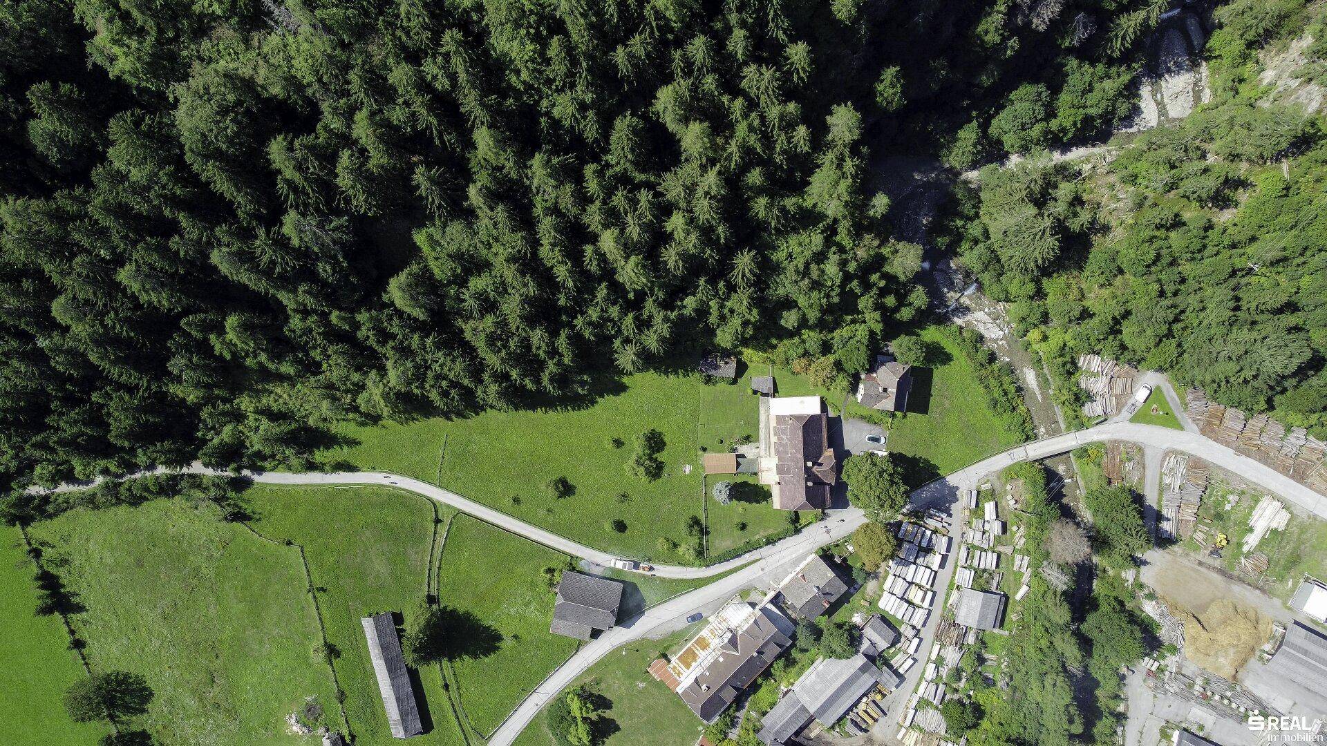 Weitläufige Luftaufnahme der ländlichen Umgebung mit Wald, Wiesen und kleinen Siedlungen.