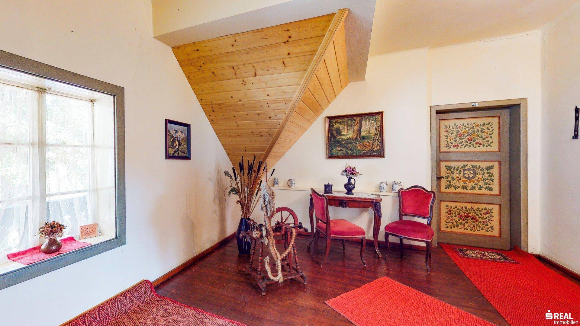 Heller Flurbereich mit Holztreppe, Holzboden und traditionell bemalten Türen.