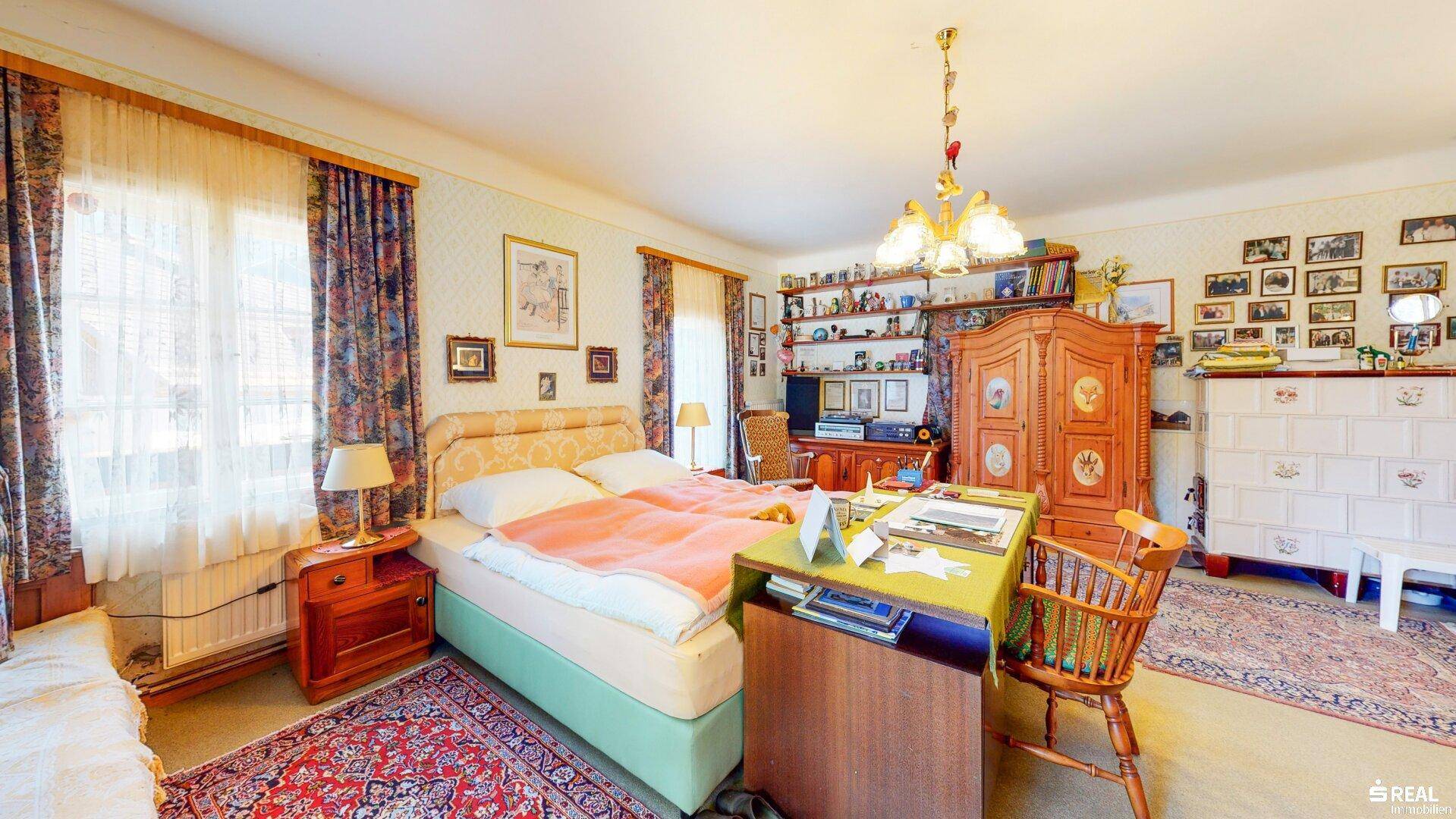 Gemütliches Schlafzimmer mit Doppelbett, traditionellen Möbeln und Blick ins Grüne.