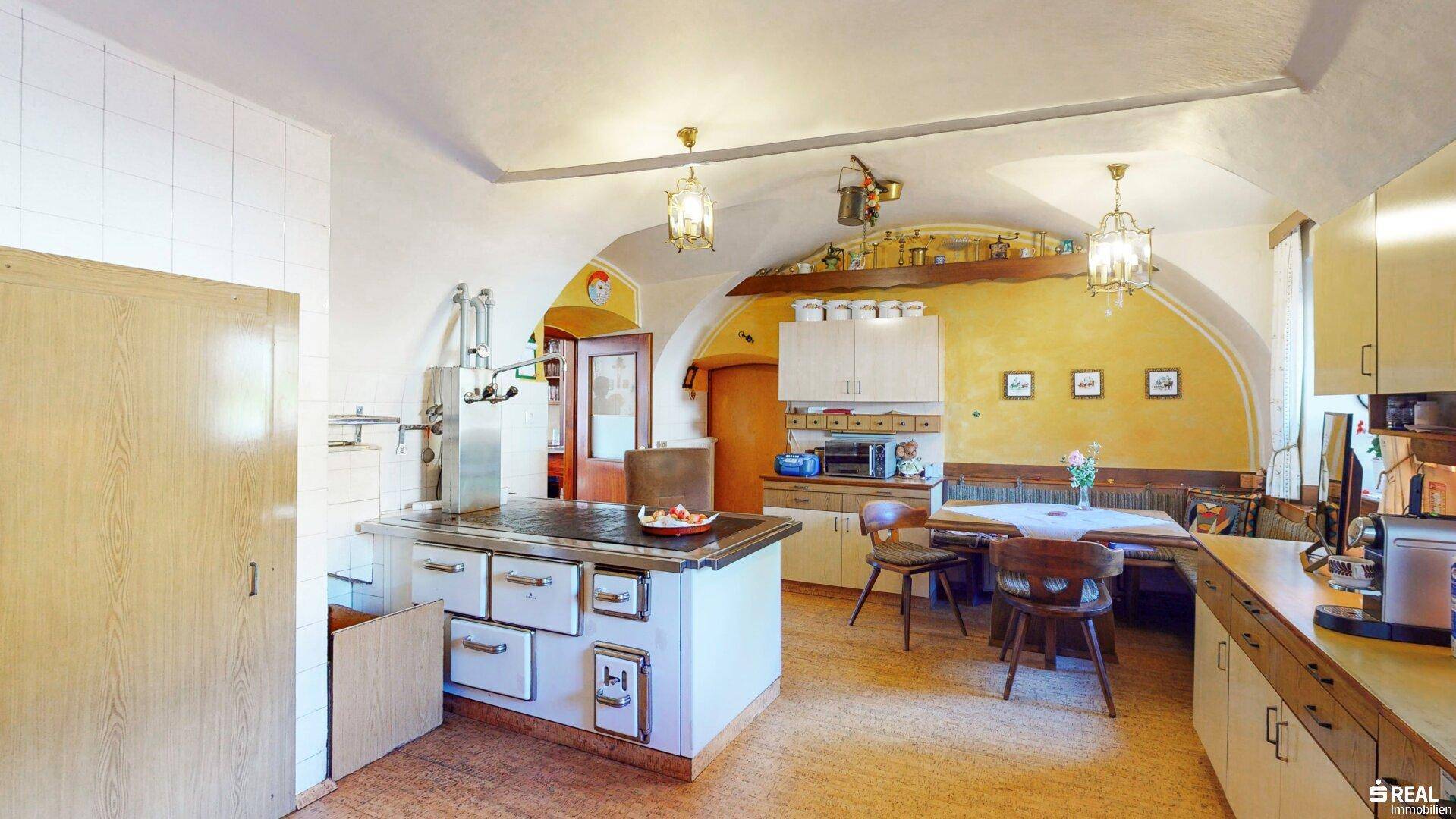 Traditionelle Küche mit Gewölbedecke, Holzofen und Essbereich im Landhausstil.