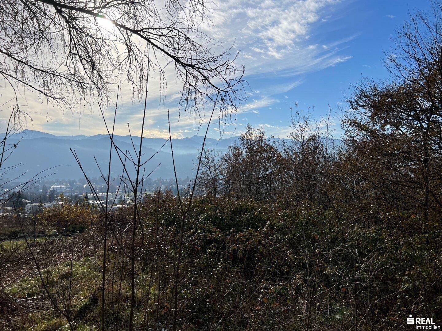 Panoramablick auf die umliegende Berglandschaft und grüne Hügel unter klarem Himmel.