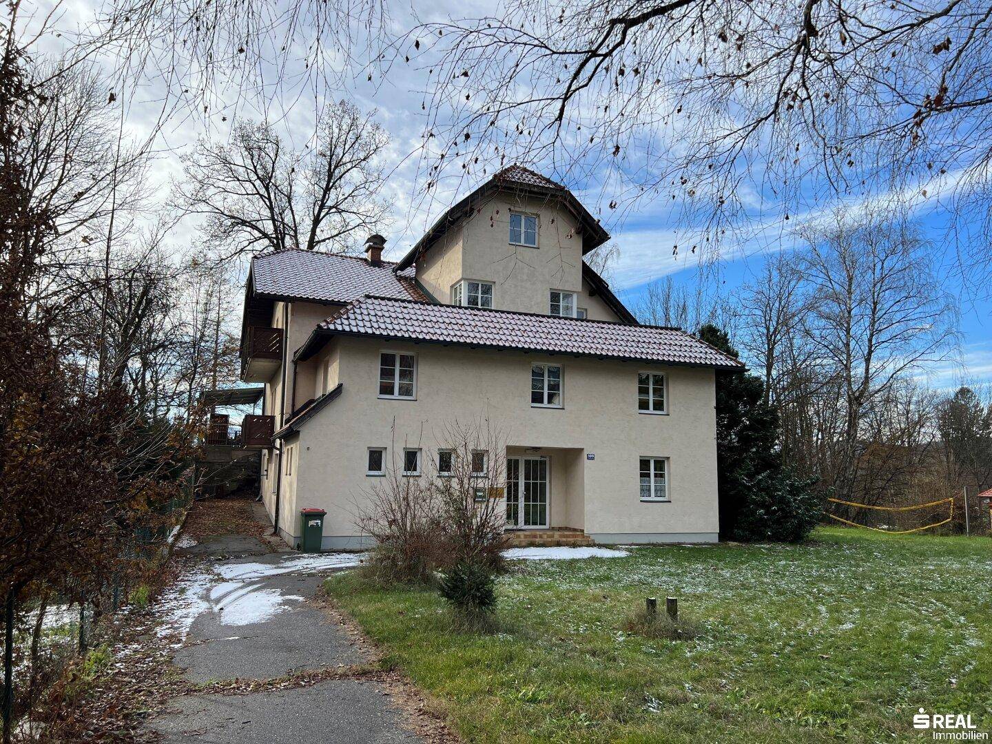 Rückansicht des Hauses mit Gartenfläche und Zugang zum Außenbereich unter blauem Himmel.
