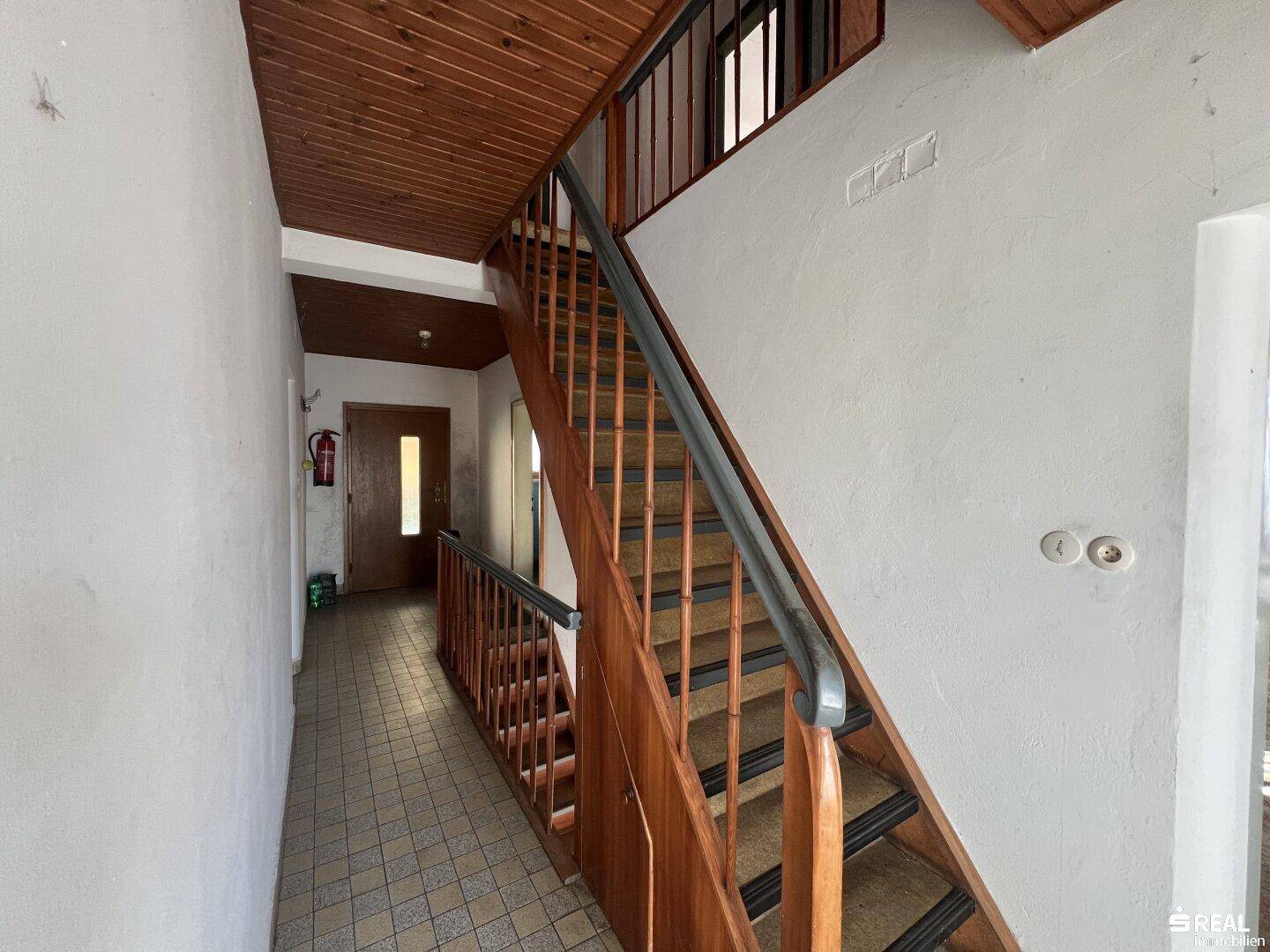 Treppenhaus mit Holzstufen und Geländer, das die verschiedenen Etagen verbindet.