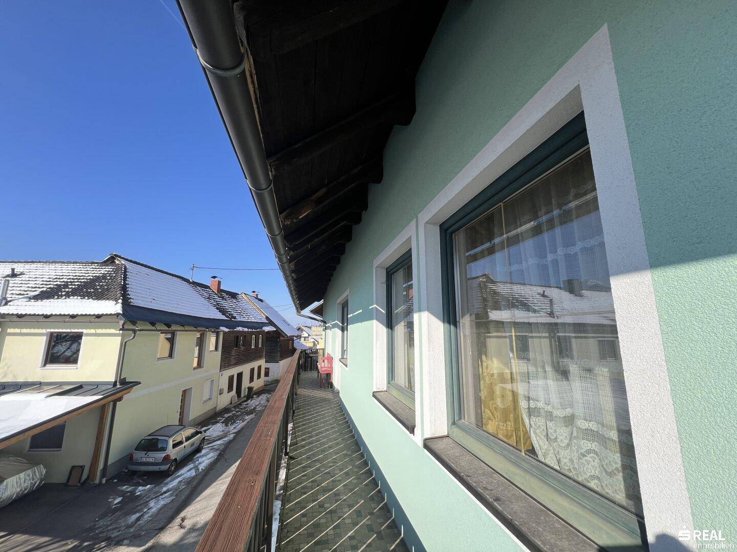 Langer Balkon mit Holzbalkonbrüstung und Blick auf die verschneite Umgebung.