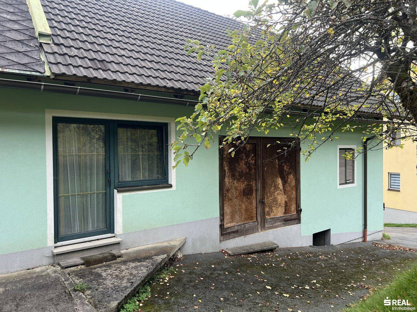 Seitenansicht des Hauses mit alten Holztüren und einem Fenster.
