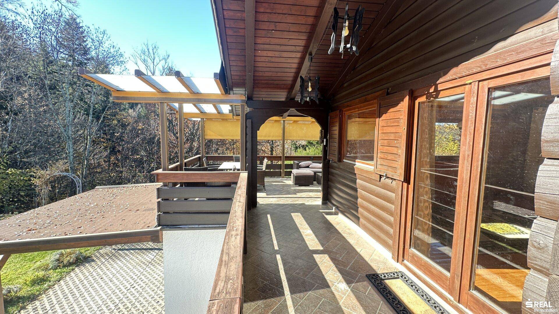Überdachter Holzbalkon mit Blick auf die umliegende Natur und viel Grün.