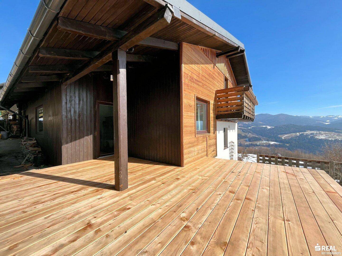 Große Holzterrasse mit weitem Bergblick, perfekt für sonnige Tage im Freien.