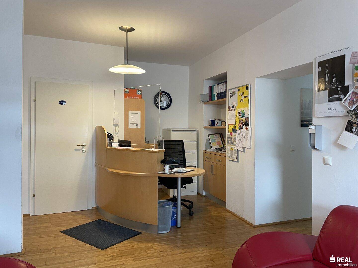 Detailansicht des Empfangsbereichs mit funktionalem Schreibtisch und Ablagemöglichkeiten, gut beleuchtet.