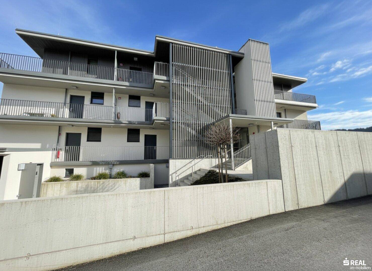 Moderne Architektur des Gebäudes mit klaren Linien, Betonwänden und Außentreppen.