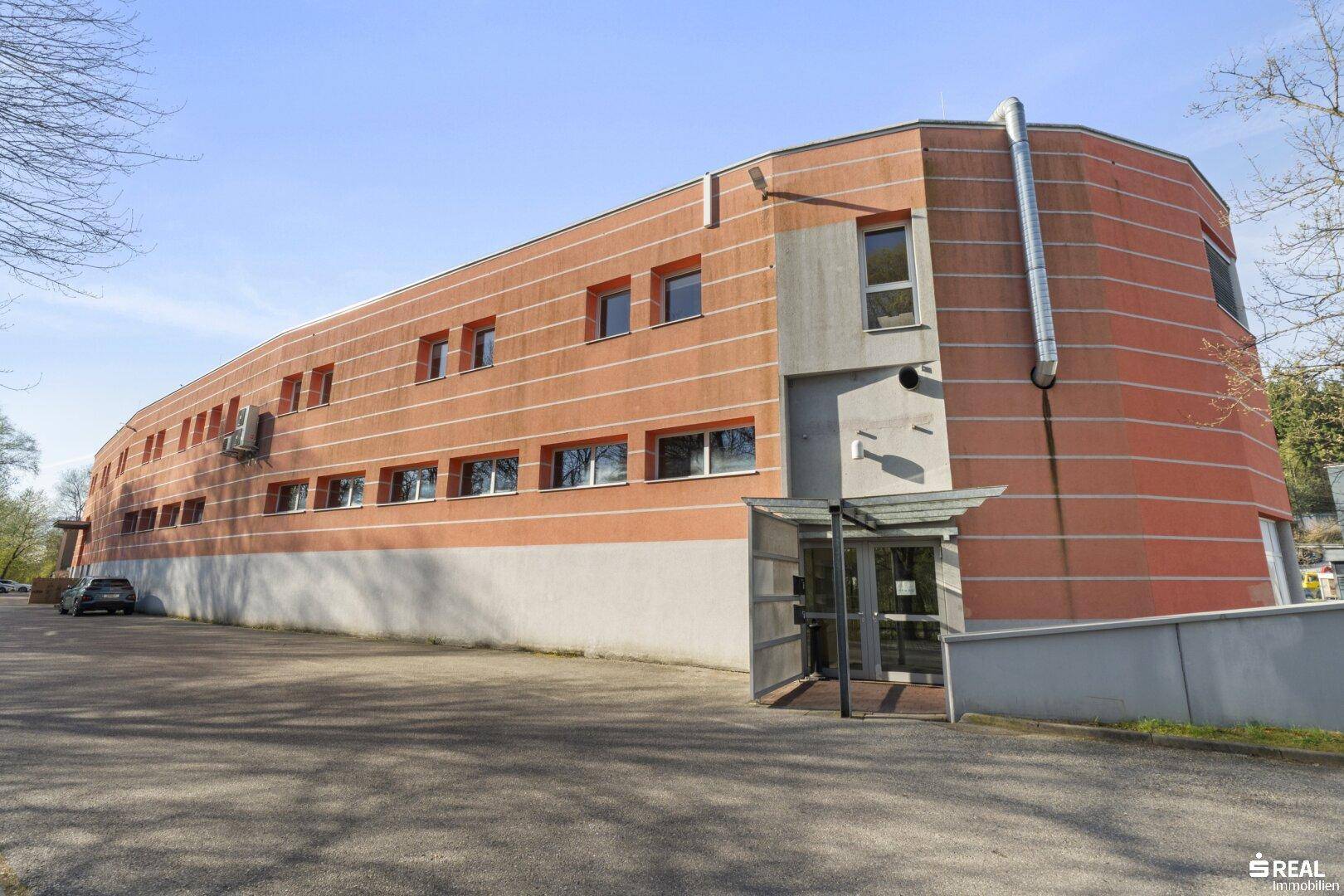 Modernes Bürogebäude mit markanter orangeroter Fassade und zahlreichen Fenstern.