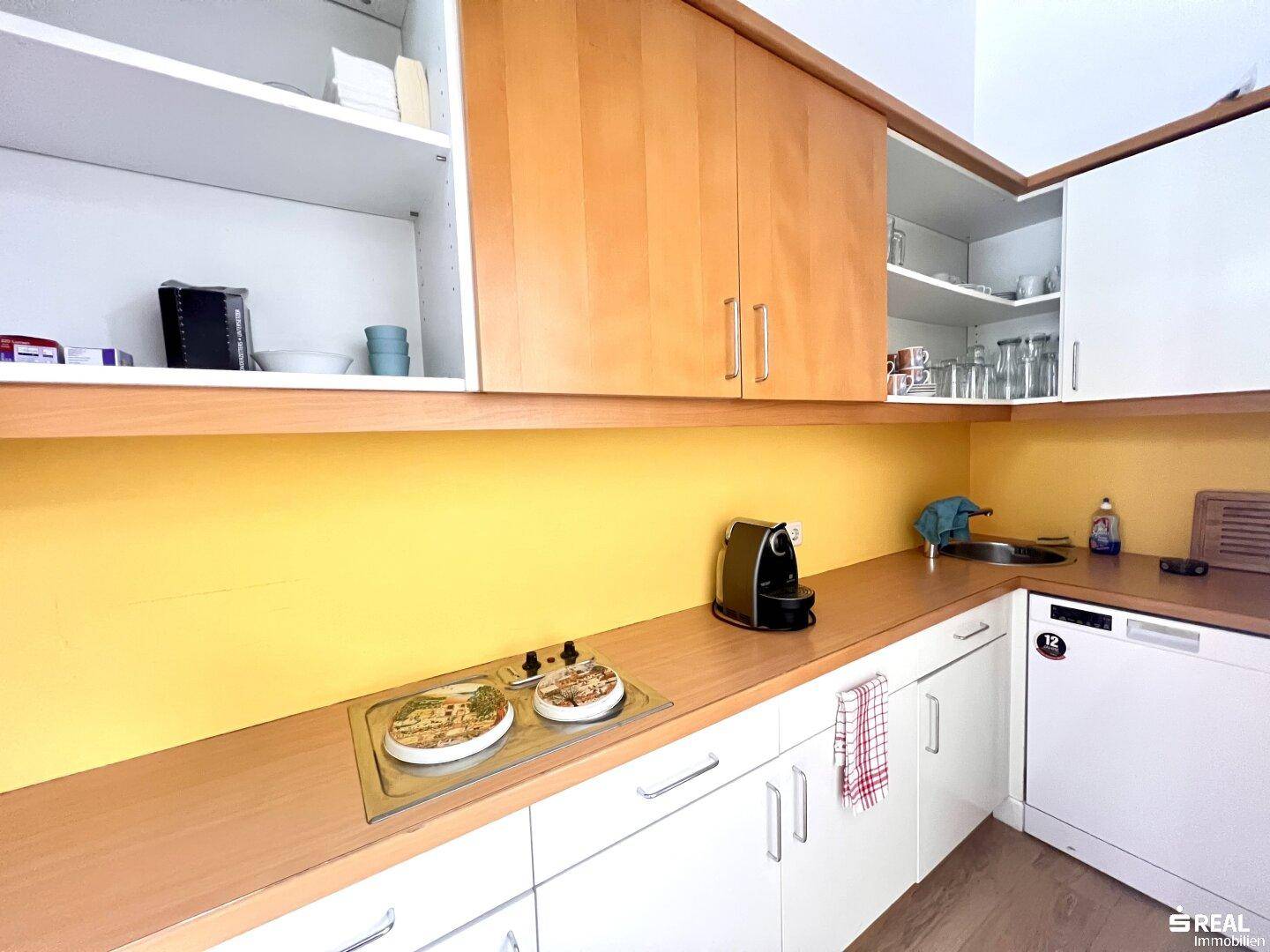 Funktionale Küchenzeile mit Holz- und weißen Schränken, Spüle und Kochfeld, ideal für Pausen.