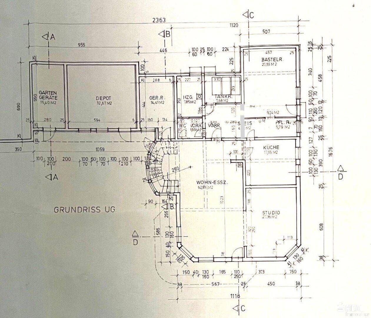 Grundriss des Untergeschosses zeigt einen Garten, ein Depot, eine Küche, einen Wohn-Essbereich, ein Studio und Hauswirtschaftsräume.