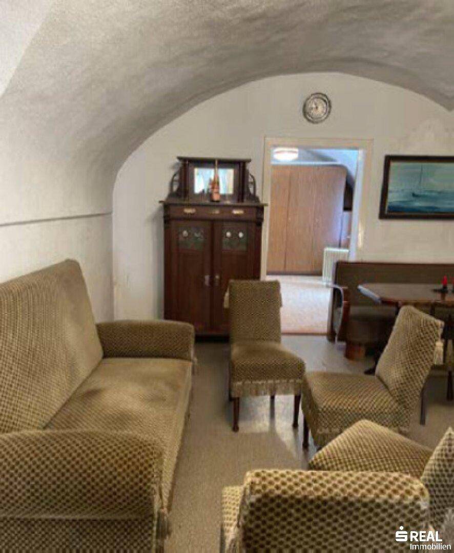 Wohnzimmer mit gewölbter Decke, Vintage-Möbeln und traditionellem Holzschrank.