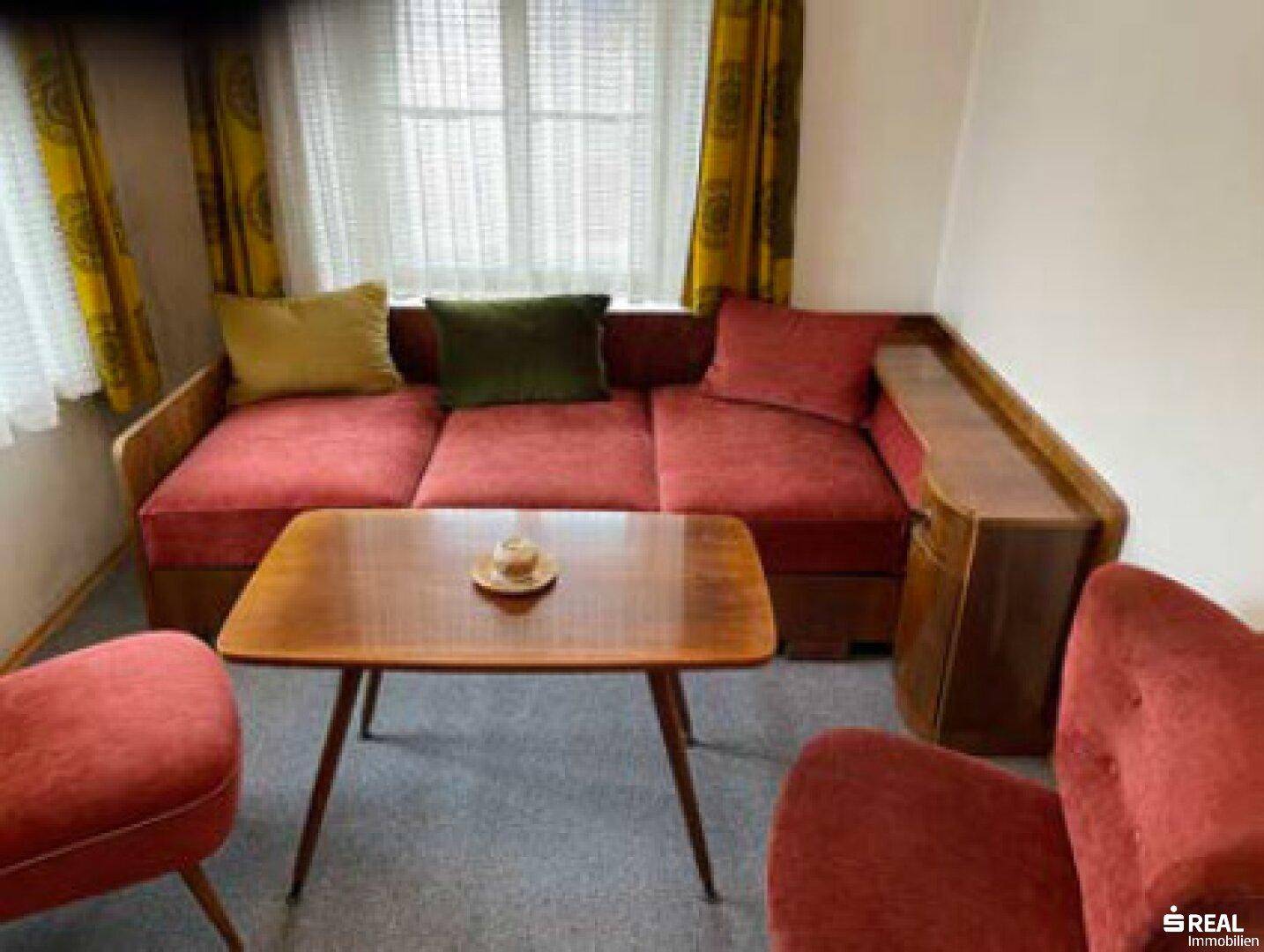 Gemütliches Wohnzimmer mit rotem Sofa, Holztisch und gelben Vorhängen im Vintage-Stil.