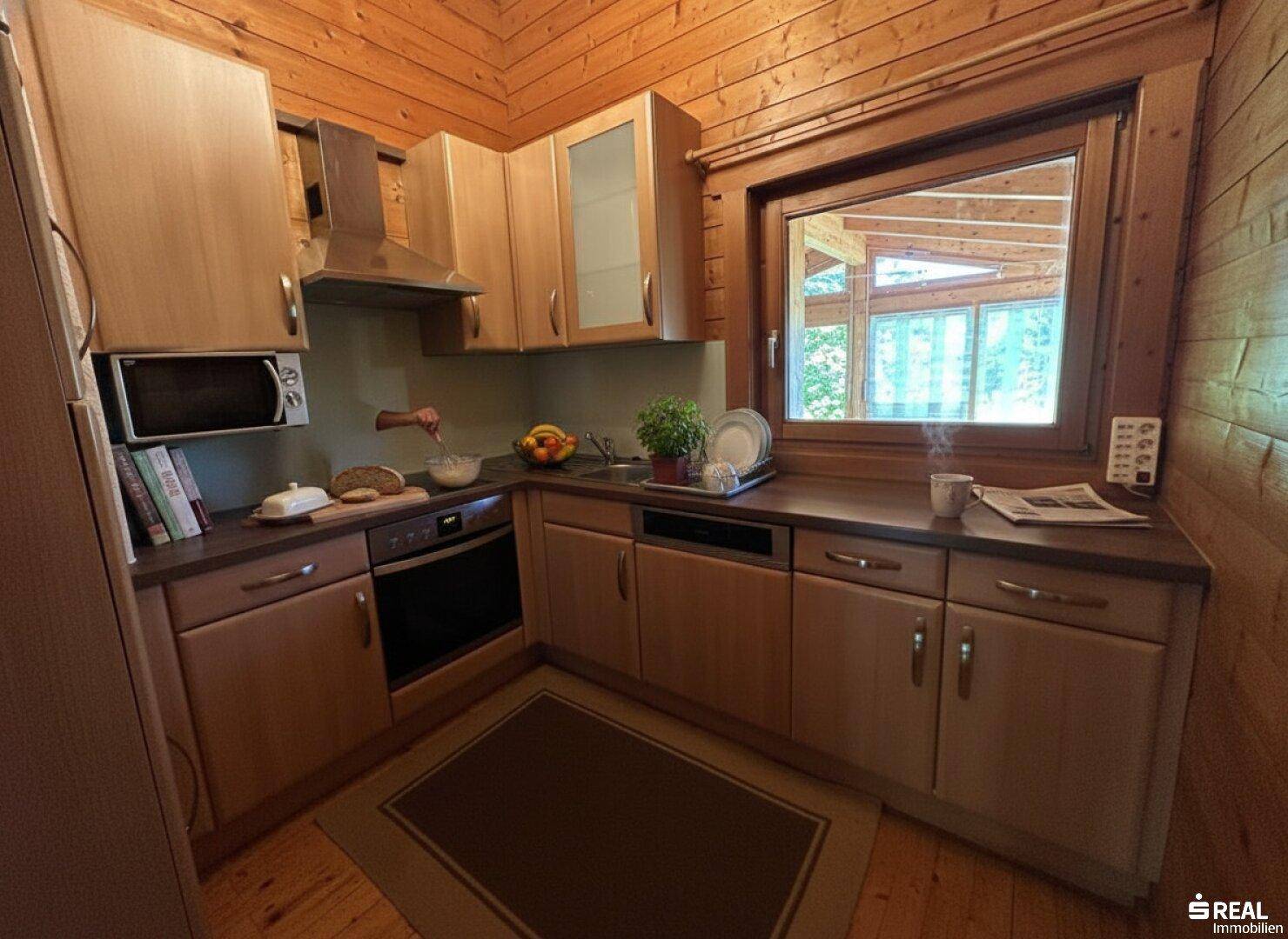 Funktionale Küche im Landhausstil mit Holzelementen, Einbaugeräten und Fenster.