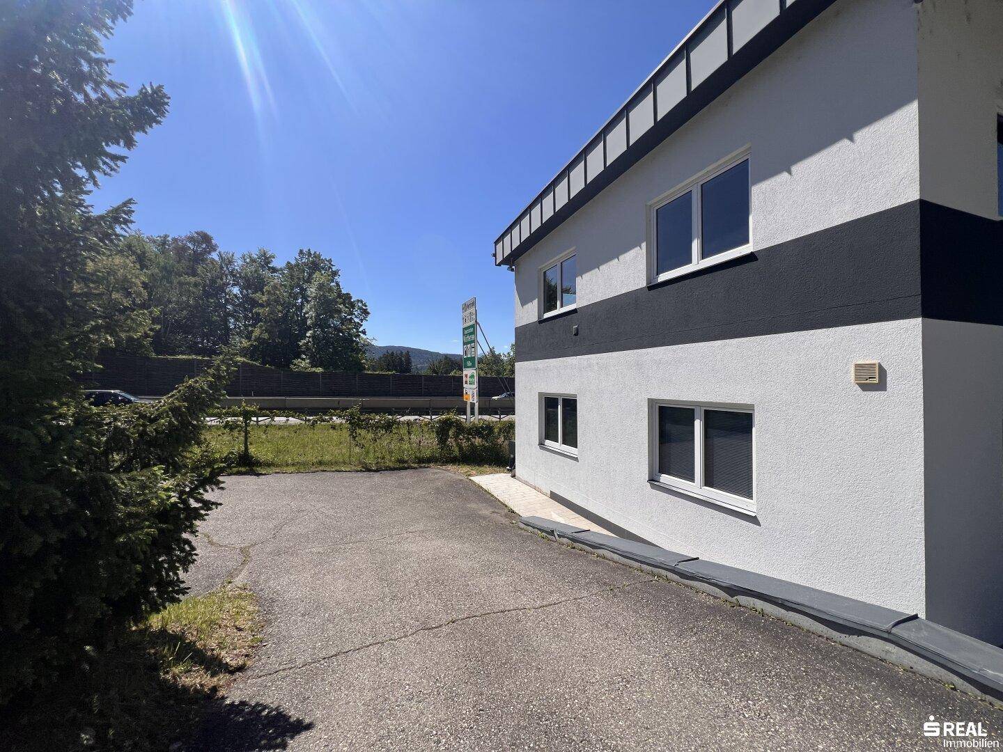 Seitenansicht des modernen Gebäudes mit weißer und schwarzer Fassade und angrenzendem Parkplatz.