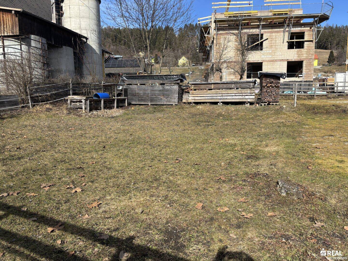Großer Gartenbereich mit gelagerten Baumaterialien und Blick auf die umliegende Landschaft.