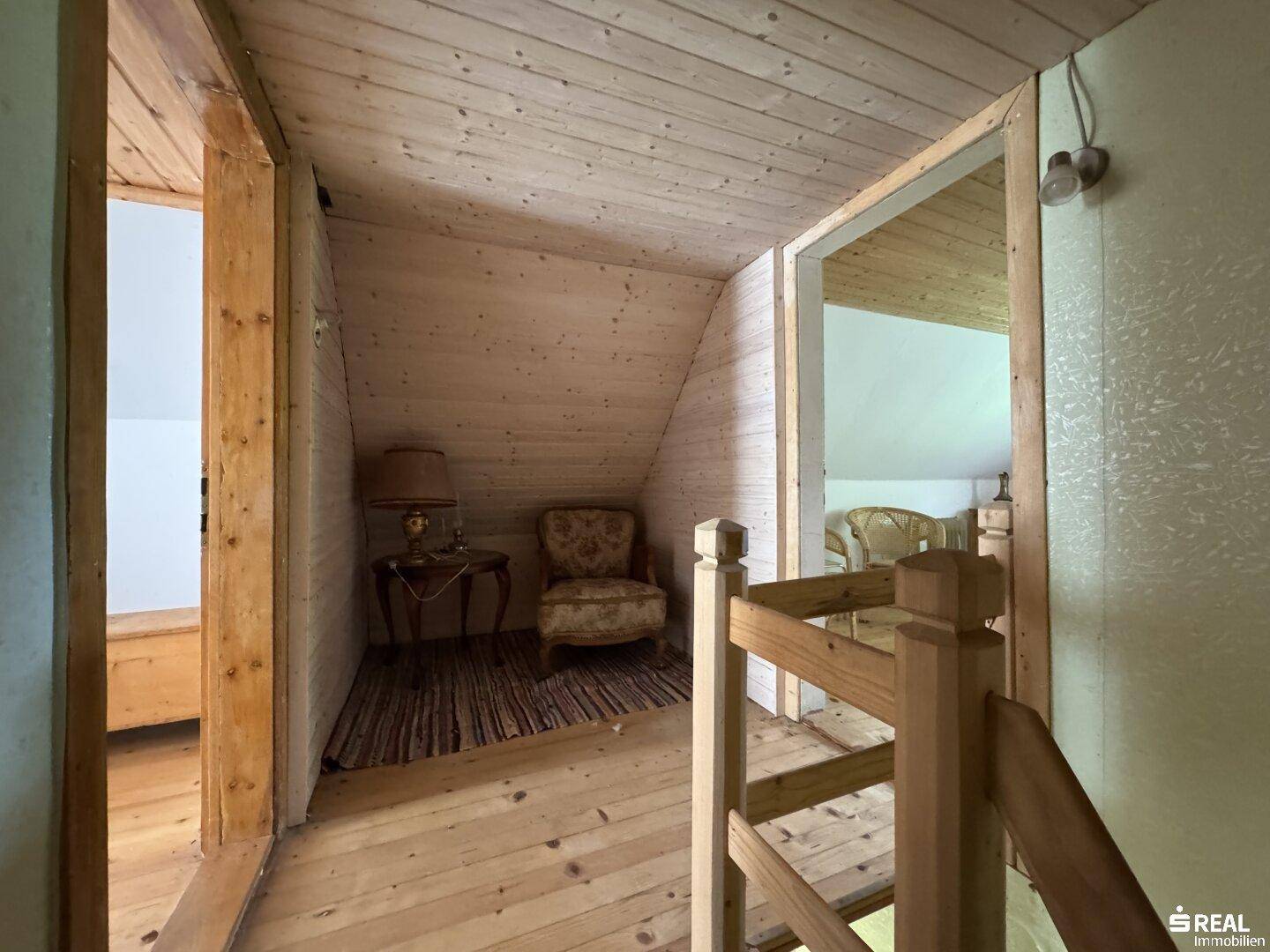 Flur im Dachgeschoss mit Holztreppe und Zugang zu weiteren Zimmern.