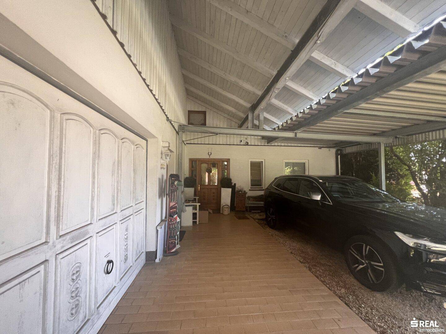 Ansicht des Hauses mit Garagentor, überdachtem Carport und dem Eingangsbereich, alles in einem traditionellen Stil.