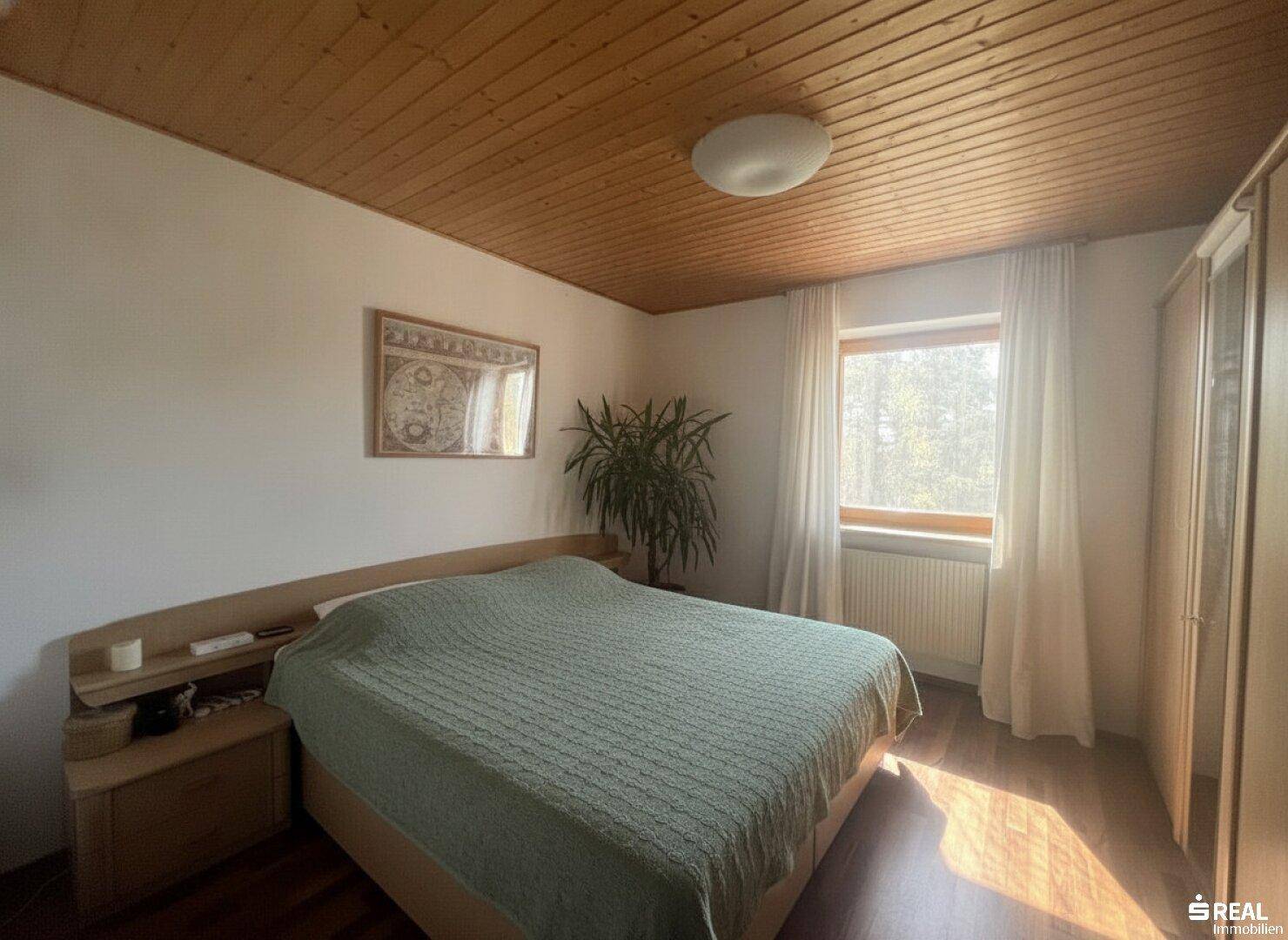 Gemütliches Schlafzimmer mit Doppelbett, Nachttischen und Kleiderschrank, ausgestattet mit Holzdecke und Holzboden.