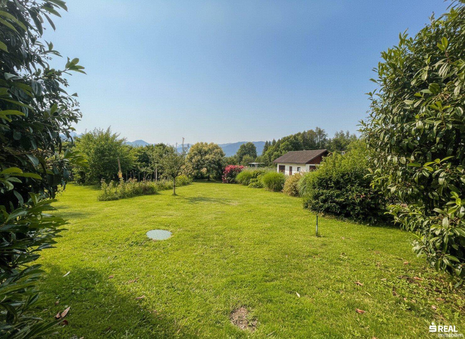 Großer, sonniger Garten mit weitläufigem Rasen und vereinzelten Bäumen, bietet viel Platz im Grünen.
