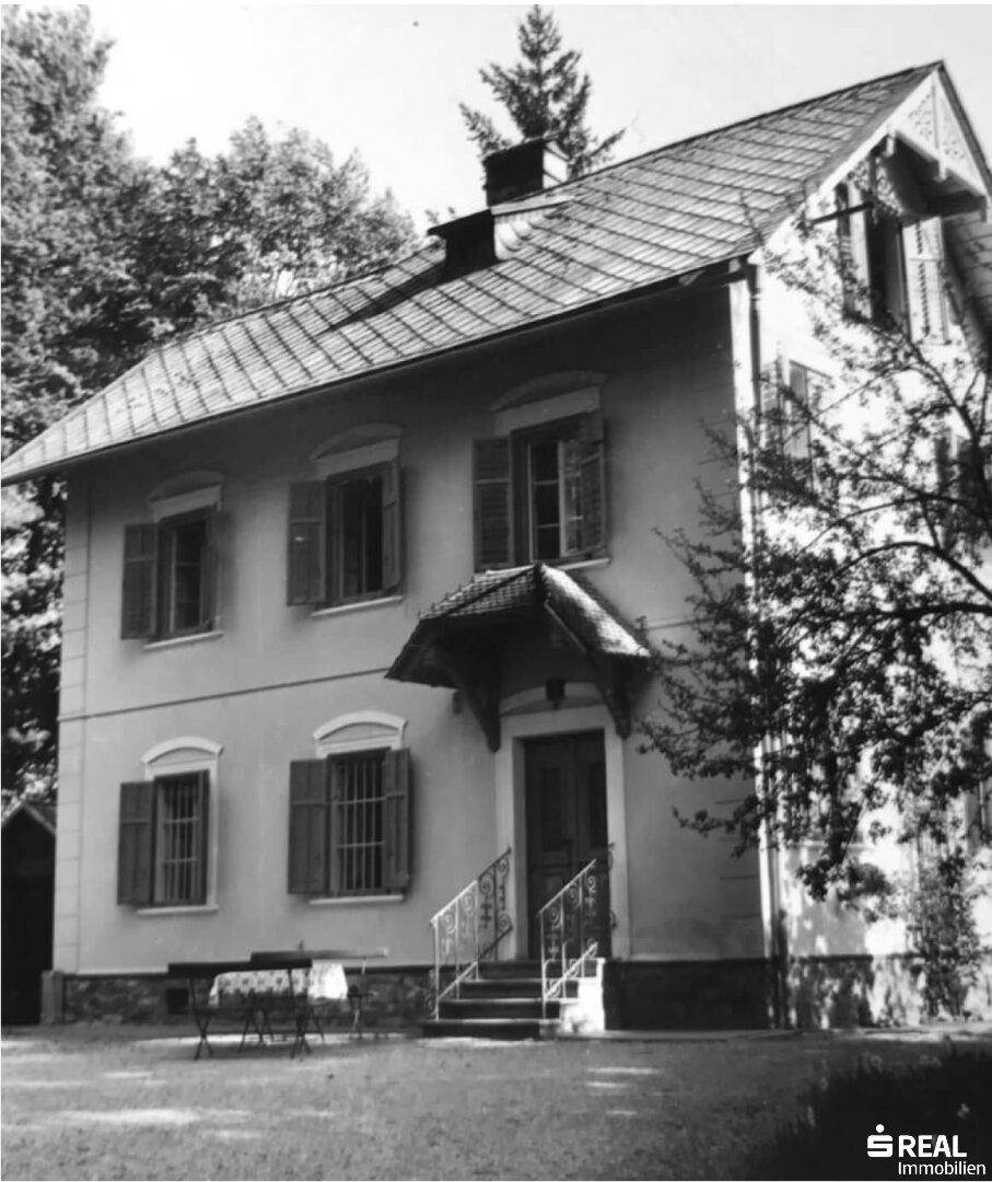 Schwarz-Weiß-Foto der Hausfassade mit Eingangsbereich, Treppe und verzierten Fensterläden.