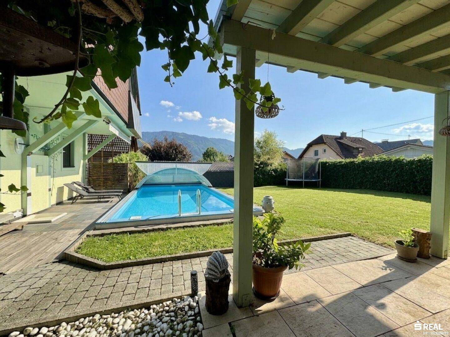 Gepflegter Garten mit Swimmingpool, Liegefläche und überdachtem Terrassenbereich.