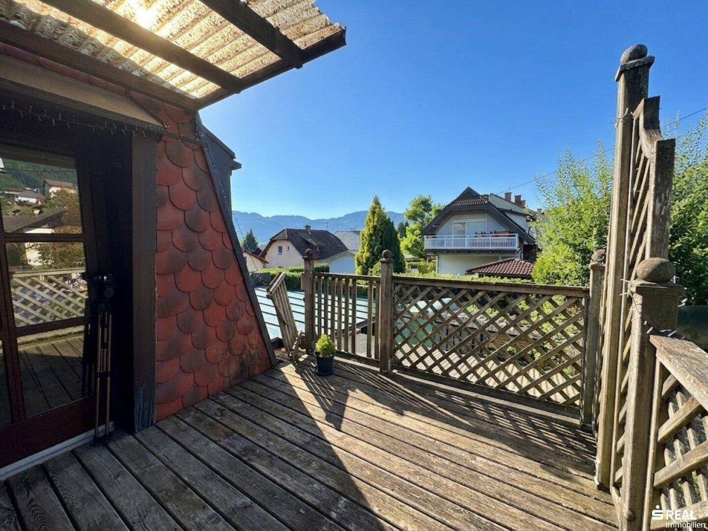 Geräumiger Holzbalkon mit Gittergeländer und weitem Blick auf die umliegende Landschaft.