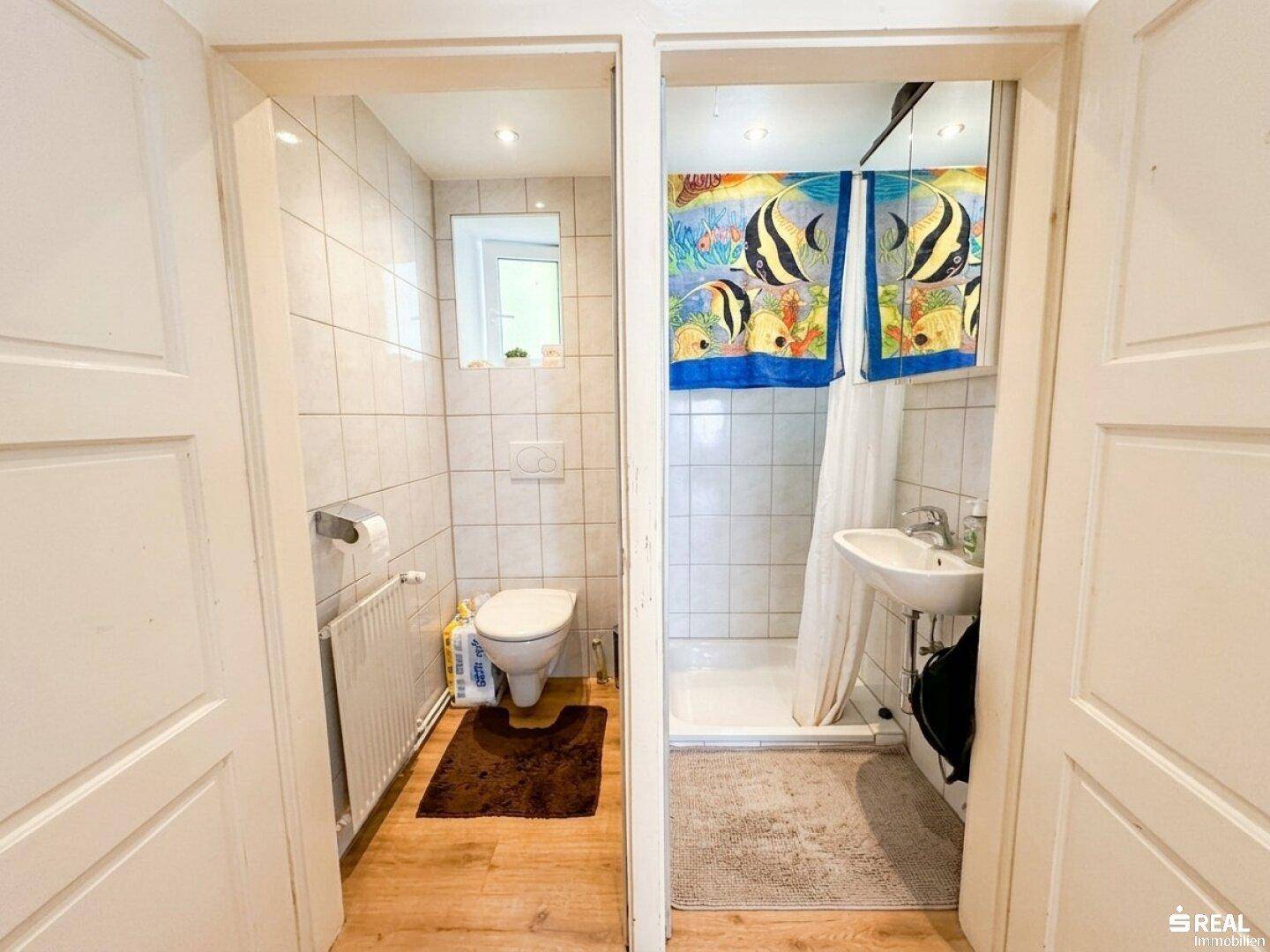 Kleines Badezimmer mit separatem WC-Bereich und Duschkabine, hell gefliest.
