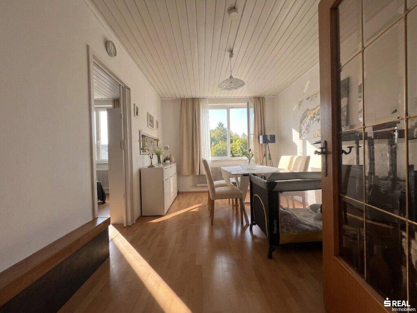Heller Essbereich mit Holztisch, Stühlen und einer Holzpaneeldecke, durchflutet von natürlichem Licht.