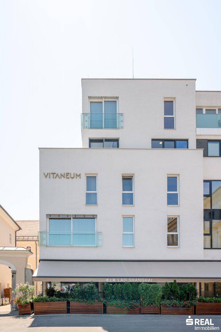 Moderne Wohnfassade mit Balkonen und großen Fenstern in urbaner Umgebung.