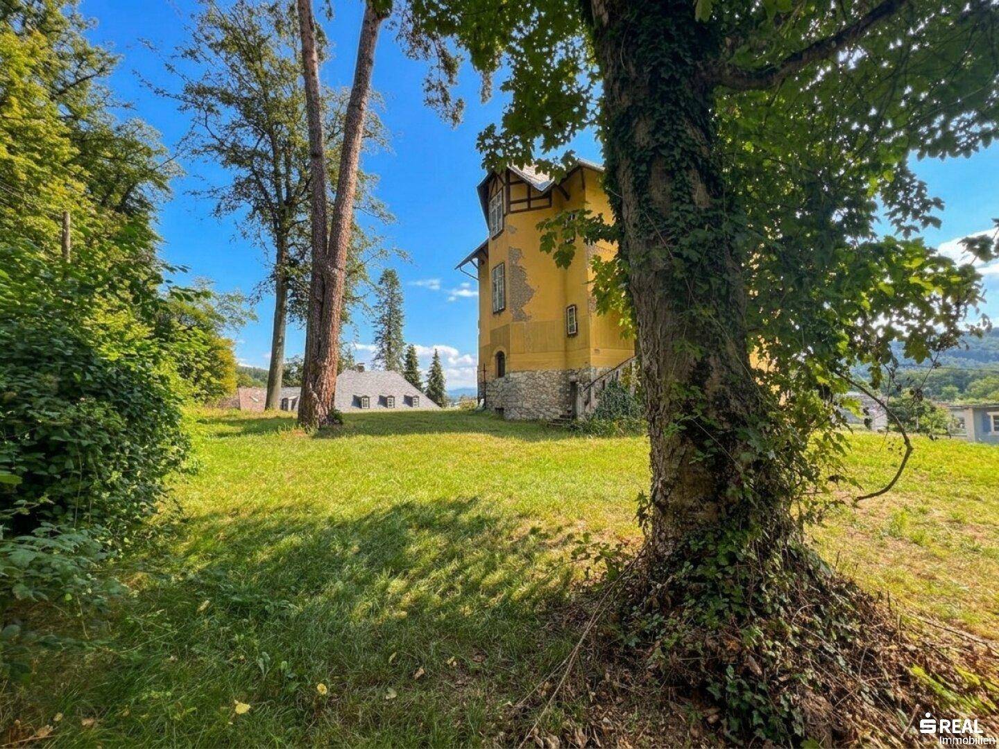 Großer, gepflegter Gartenbereich mit altem Baumbestand und Blick auf die historische Villa.