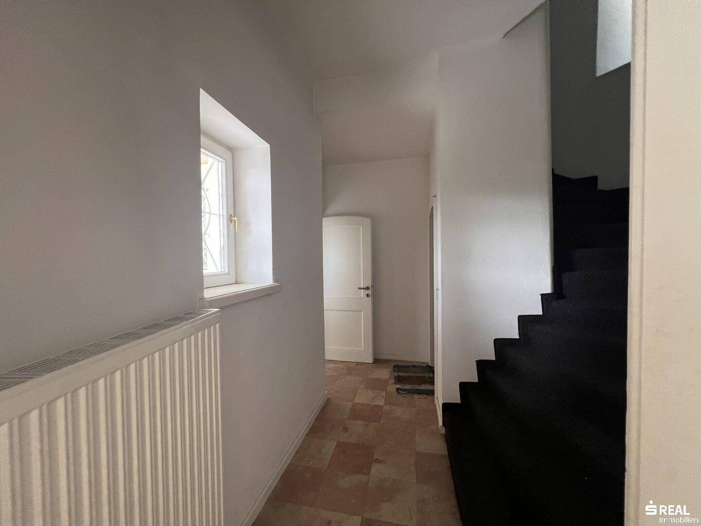Flur mit Terrakotta-Boden und Treppe, der auf eine Renovierung wartet.