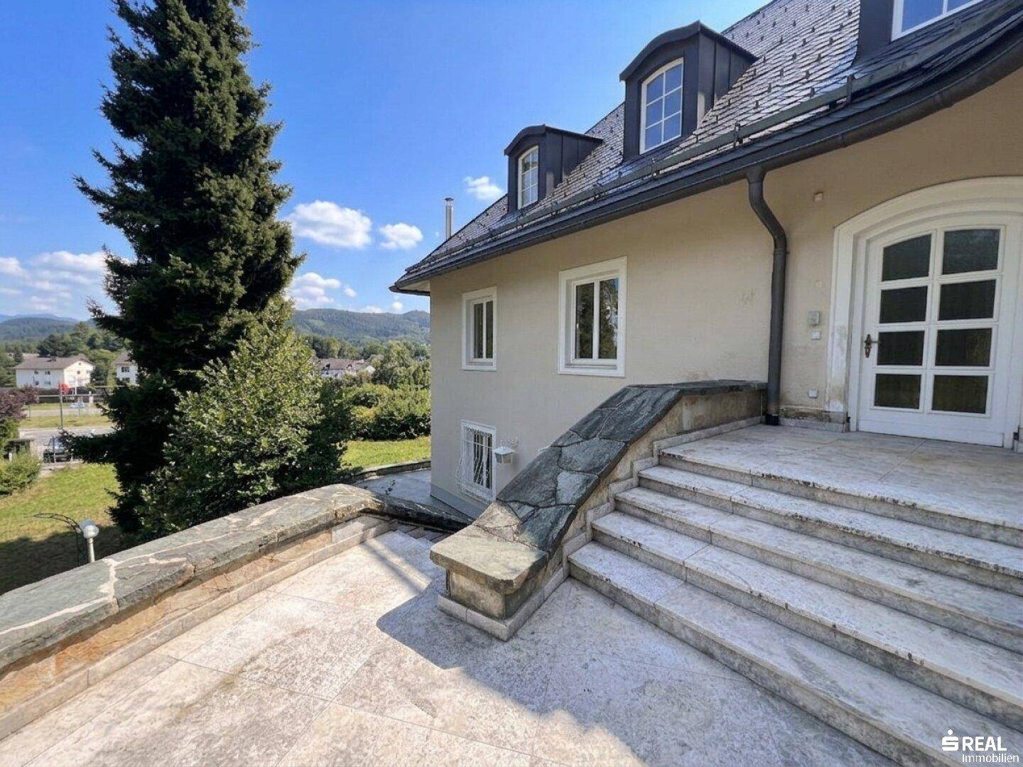 Historische Villa mit Steintreppe und weitem Blick über die Landschaft.