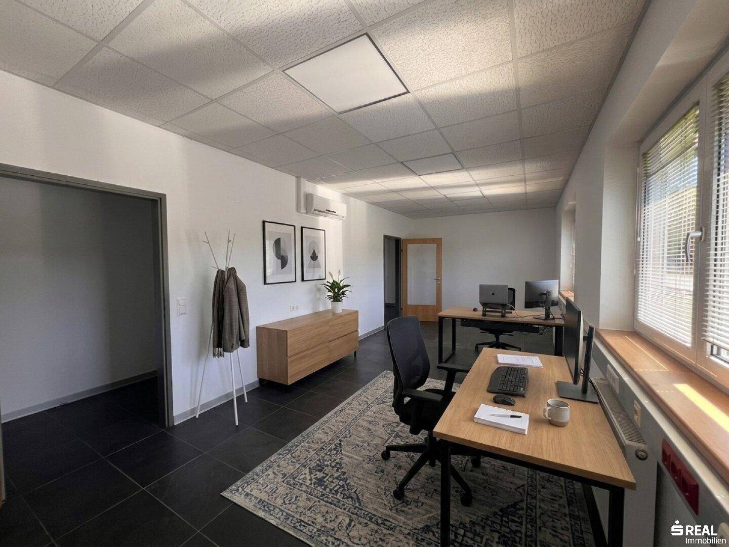 Großes, offenes Büro mit mehreren Arbeitsplätzen, modernen Möbeln und viel Tageslicht.