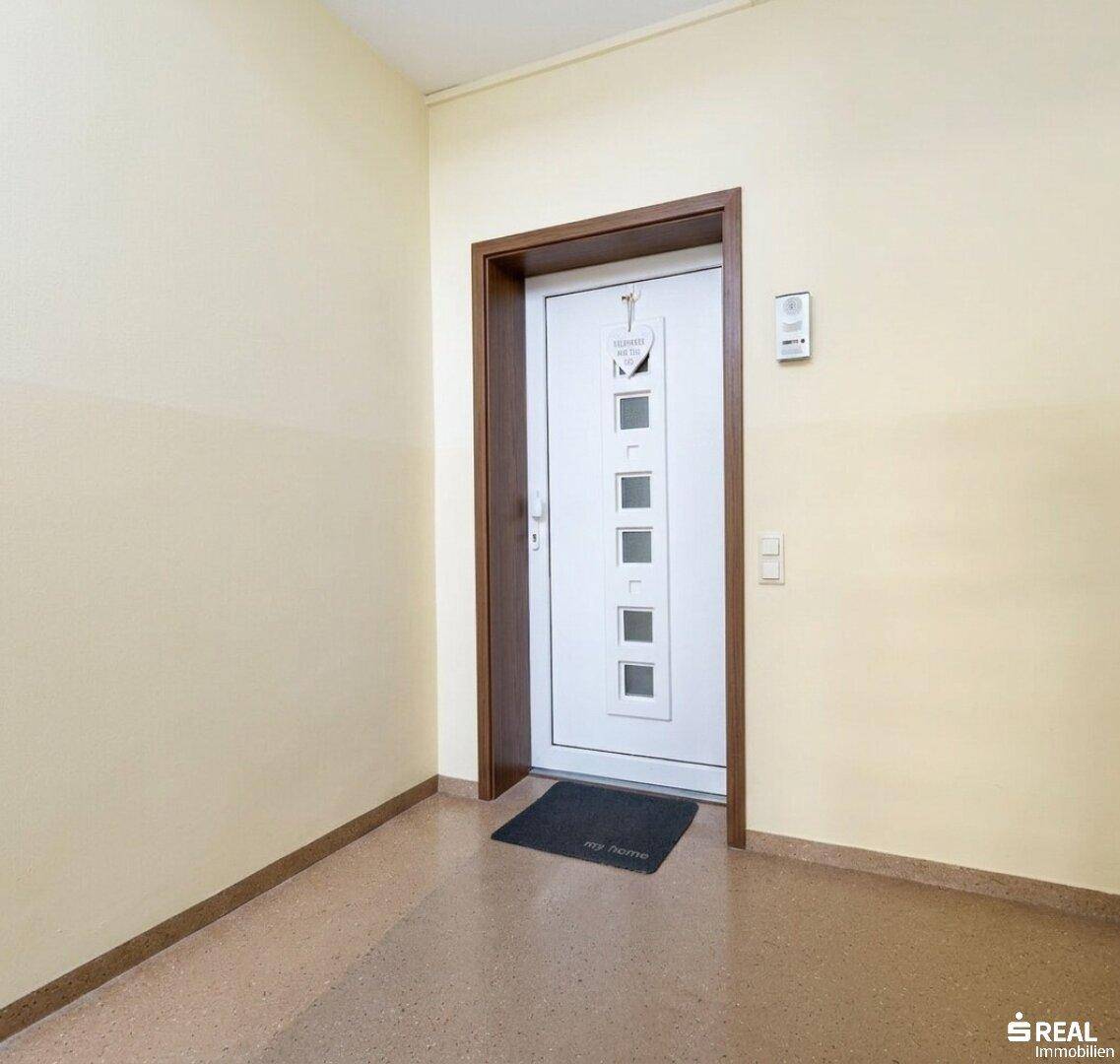 Eingangsbereich der Wohnung mit heller Tür und robustem Fliesenboden.