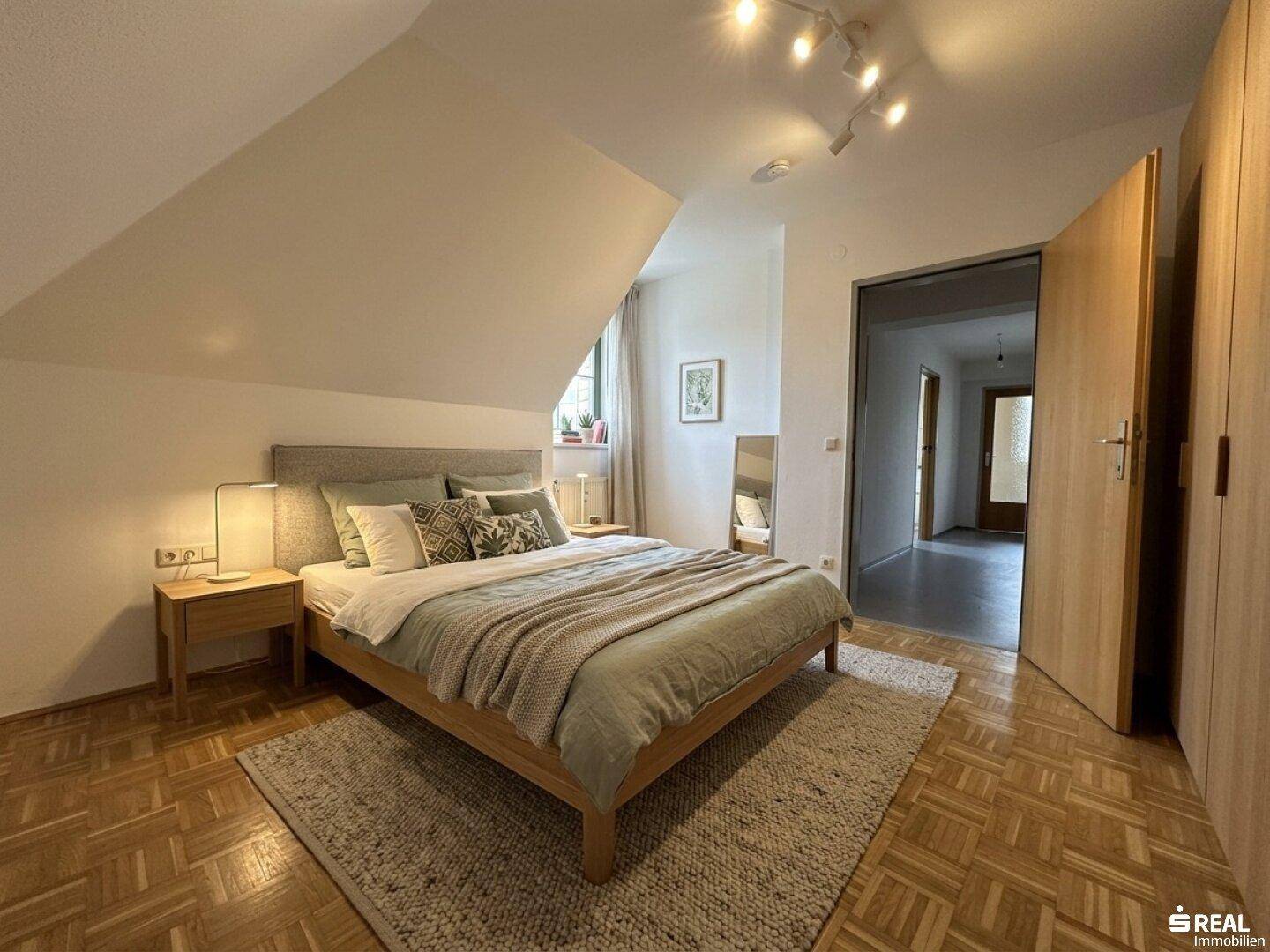 Virtuell eingerichtetes Schlafzimmer mit Parkettboden, Dachschräge und modernem Bett.