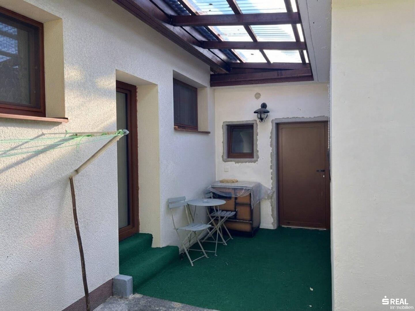 Überdachte Terrasse mit Sitzgelegenheiten und Wäscheleine, ideal für entspannte Stunden im Freien.