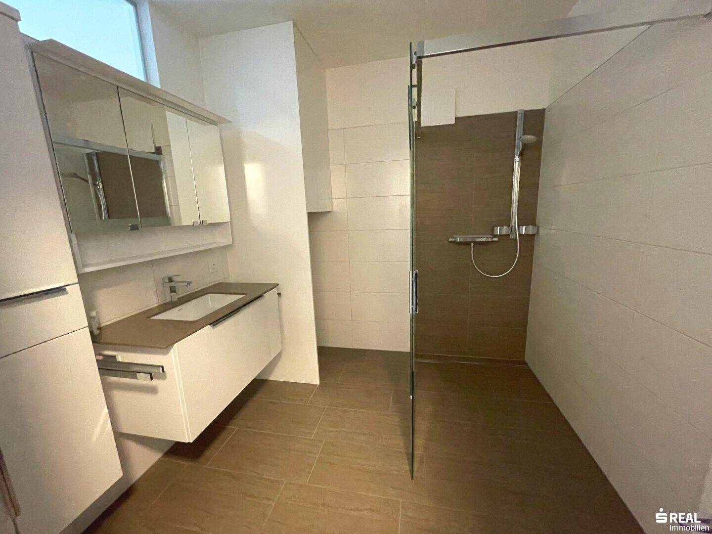 Modernes Badezimmer mit ebenerdiger Dusche, schwebendem Waschtisch und Spiegelschrank.